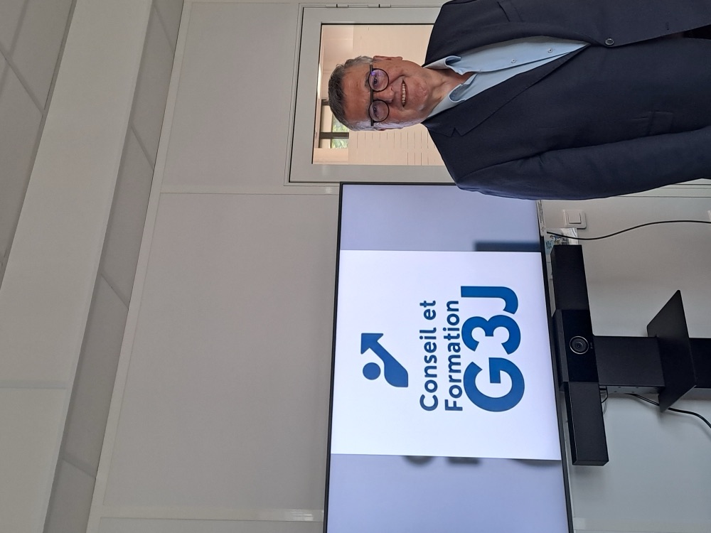 Philippe Gérard devant l’écran affichant le logo Conseil et Formation G3J